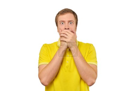 Frightened young man in yellow T-shirt holding hands over his face isolated on white background. Scared guy in yellow Polo T-shirt gesticulating his hands, afraid, negative emotion