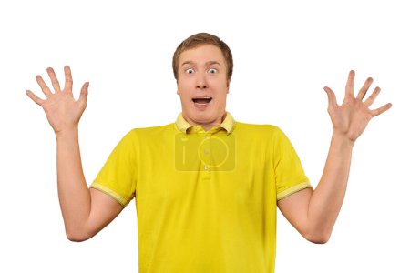 Téléchargez les photos : Scared young man in yellow T-shirt with hands up, white isolated background. Afraid facial expression of young man in yellow Polo isolated on white background. Portrait of frightened man - en image libre de droit