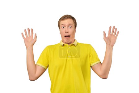 Téléchargez les photos : Scared young man in yellow T-shirt with hands up, white isolated background. Afraid facial expression of young man in yellow Polo isolated on white background. Portrait of frightened man - en image libre de droit