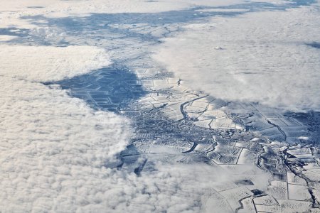 Téléchargez les photos : Aerial view over clouds top to snow covered rivers, fields and roads, winter fresh frosty air. Beautiful hazed sky aerial view to Earth troposphere, snowy abstract background texture - en image libre de droit