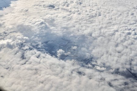 Téléchargez les photos : Breathtaking over clouds view from aircraft window, thick white blue clouds looks like soft foam, overcast with fresh frosty air. Beautiful cloudy sky view to troposphere, heavy cloudiness - en image libre de droit