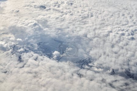 Téléchargez les photos : Over clouds top view from aircraft window, thick white blue clouds looks like soft foam, overcast with fresh frosty air. Beautiful cloudy sky view to troposphere, heavy cloudiness - en image libre de droit