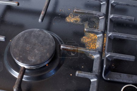 Photo for Unclean dirty kitchen black stove after soup boil over, dried food spots, fat stains dry food leftovers. Black stainless cooktop with gas burner stained in remains of fat food and oil splatters - Royalty Free Image