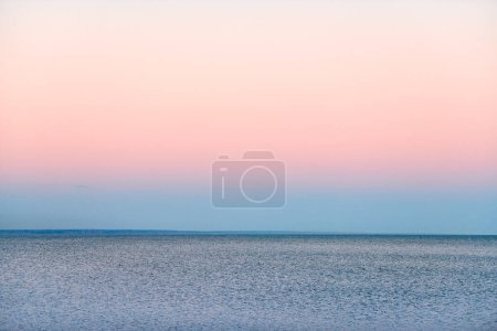 Foto de Atmospheric romantic pink red sea sunset sky above blue quiet water, minimalistic peaceful seascape, beautiful background copy space. Pinkish sky above Azov sea horizon, Rostov on Don region in Russia - Imagen libre de derechos