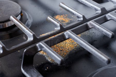 Photo for Dirty unclean kitchen black stove with dried food spots, fat stains and soup boil over leftovers. Black stainless cooktop with gas burner stained in remains of fat food, fry spots and oil splatters - Royalty Free Image