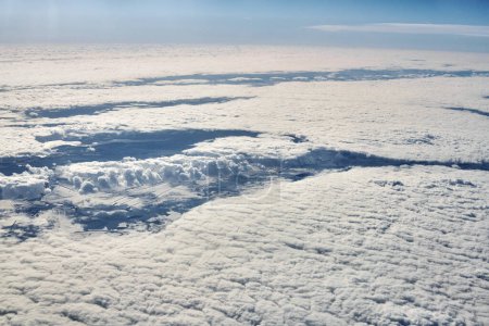 Téléchargez les photos : Aerial cloudscape view over top clouds to snow covered rivers, roads, cities and fields, winter fresh air. Beautiful hazed sky aerial view to Earth troposphere, snowy abstract background texture - en image libre de droit