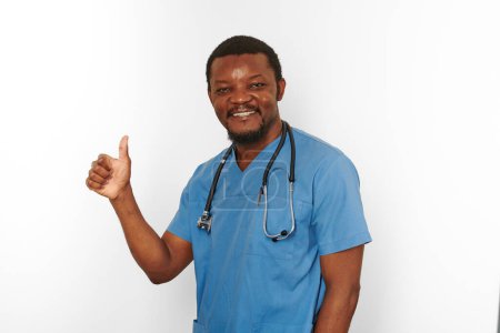 Téléchargez les photos : Smiling black surgeon doctor bearded man in blue coat with stethoscope makes thumbs up like gesture, isolated on white background. Happy adult black african american practicing surgeon portrait - en image libre de droit