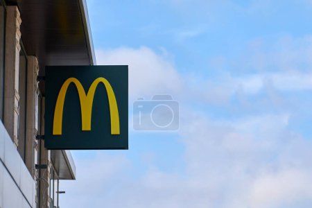 Photo for Rostov on Don, Russia - 02.21.2022 - McDonalds logo on fast food restaurant branch with right copy space on blue sky, yellow macdonald logo of popular fast food company. Mac donald brand logotype - Royalty Free Image