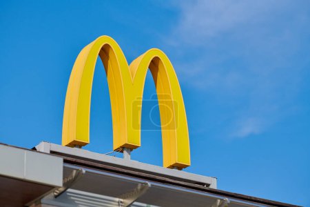 Photo for Rostov on Don, Russia - 02.21.2022 - McDonalds logo on roof of fast food restaurant branch, yellow macdonald logo of popular fast food company. Mac donald brand logotype above entrance to cafe - Royalty Free Image