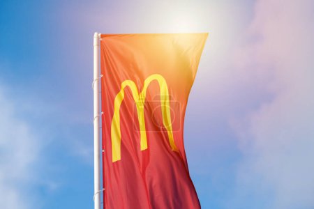 Photo for Rostov on Don, Russia - 02.21.2022 - McDonalds red flag with logo of fast food restaurant branch, roadside flowing in wind flag with yellow macdonald logo of fast food company blue sky background - Royalty Free Image