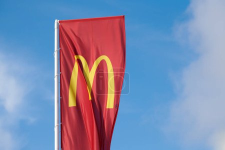 Photo for Rostov on Don, Russia - 02.21.2022 - McDonalds red flag with logo of fast food restaurant branch, roadside flowing in wind flag with yellow macdonald logo of fast food company blue sky background - Royalty Free Image