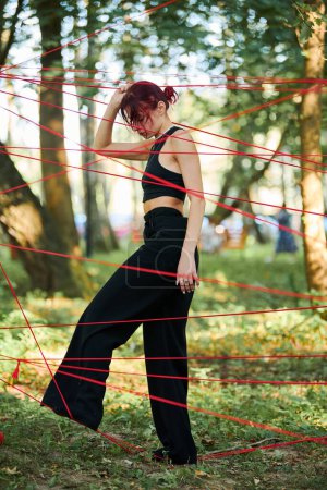 Téléchargez les photos : Svetlogorsk, Russie - 13.08.2022 - Interprète actrice prise dans les cordes rouges dans le parc performance d'art en plein air dans la forêt sur la liberté de choix de l'homme. Extérieur forêt art moderne performance - en image libre de droit