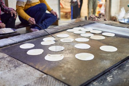 Foto de Cocina de chapati panes planos redondos para el langar en el templo sikh gurudwara, muchos panes planos roti sin cocer hechos de harina de trigo integral de cantera, pan tradicional indio barato sin levadura - Imagen libre de derechos