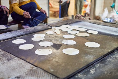 Téléchargez les photos : Cuisson de pains plats ronds chapati pour langar dans le temple gurudwara sikh, de nombreux pains plats roti non cuits fabriqués à partir de farine de blé entier moulue en pierre, pain traditionnel indien sans levain pas cher - en image libre de droit