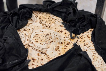 Téléchargez les photos : Lot de pains plats ronds chapati en sac noir pour langar dans le temple gurudwara sikh, de nombreux pains plats roti savoureux fabriqués à partir de farine de blé entier moulue en pierre, pain traditionnel indien sans levain pas cher - en image libre de droit