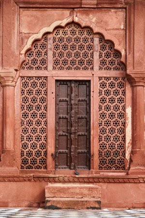 Antike Tür mit dekorativen Wandelementen des Taj Mahal, schöne antike Wanddekorationen, die geometrische Muster darstellen, alte rote Sandsteine handgefertigte Ornamente Dekoration in Taj Mahal Wahrzeichen Gebäude