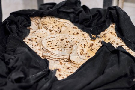 Photo for Batch of chapati round flatbreads in black bag for langar in sikh gurudwara temple, many tasty roti flatbreads made from stoneground whole wheat flour, traditional indian cheap unleavened bread - Royalty Free Image