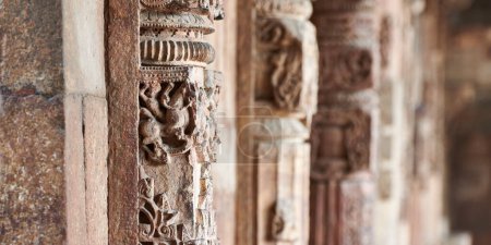 Photo for Stone columns with decorative bas relief of Qutb complex in South Delhi, India, close up pillars in ancient ruins of mosque landmark, popular touristic spot in New Delhi, ancient indian architecture - Royalty Free Image