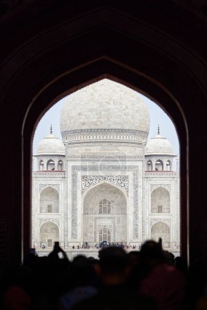 Photo for Archway of main gateway in Taj Mahal entrance with tourists silhouettes, view to Taj Mahal marble mausoleum landmark through arch, massive influx of tourists in India, Taj Mahal tourist season - Royalty Free Image