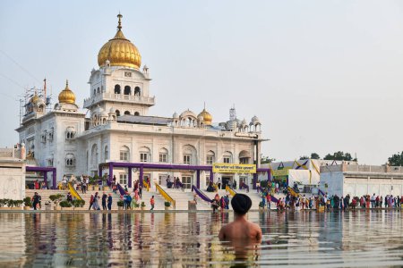 Photo for New Delhi, India - 10.11.2022 - Sikh prays in holy pond Sarovar of Gurudwara Bangla Sahib temple in New Delhi, back view of Sikh pilgrim stays in water worships in popular touristic spot in Delhi - Royalty Free Image