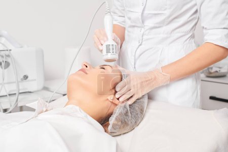 Beautician makes cryotherapy for rejuvenation woman face, anti aging cosmetic procedure with in beauty spa salon. Cosmetologist makes cryo therapy lifting with for skin rejuvenation and smoothing