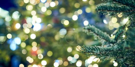 Photo for Christmas tree covered snow with yellow garlands lights and bokeh copy space, outdoor xmas green tree with decorative garlands, outdoor winter holiday atmosphere. Festive Christmas tree decorations - Royalty Free Image