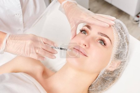 Photo for Cosmetologist makes fillers injection for lips augmentation and volume, non surgical cosmetic procedure in beauty salon. Beautician specialist hands in gloves makes treatment injection with syringe - Royalty Free Image