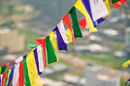 Colorful Tibetan prayer flags on blurred Kathmandu cityscape background symbolizing cultural value and spiritual heritage of Nepali region, connection between earthly and spiritual realms