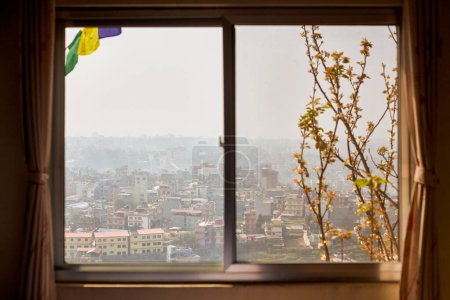 Blick auf Kathmandu aus dem Hotelfenster durch urbanen Dunst mit vielen Flachbauten, Stadtbild schafft eine ätherische Atmosphäre in der Bergluft, Luftverschmutzung in Kathmandu