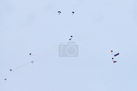 Airborne forces paratroopers soaring holding Flag of Russia and flags of military units, military exercise for celebration of Airborne Forces Day with formation landing, army airborne division descend