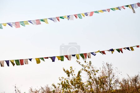 Des drapeaux de prière tibétains colorés flottent d'anciennes prières dans un vent de montagne serein au sommet d'une haute colline sur fond de ciel bleu, symbolisant l'énergie spirituelle tranquillité paisible