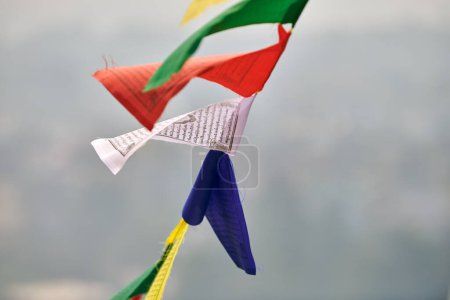 Drapeaux de prière tibétains colorés sur fond flou de paysage urbain de Katmandou symbolisant la valeur culturelle et le patrimoine spirituel de la région népalaise, connexion entre les royaumes terrestres et spirituels