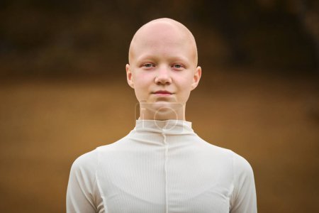Photo for Portrait of young hairless girl with alopecia in white cloth on autumn park background, bald pretty teenage girl symbolizing acceptance individuality and challenging conventional standards of beauty - Royalty Free Image