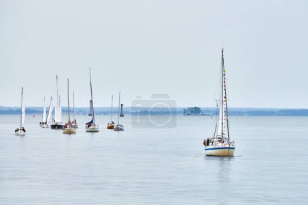 Photo for Parade of yachts along shore, several motor sailers yachts sailing along coast with lowered sails symbolizing nautical grace, joy of sailing and connection between sea enthusiasts and vast ocean - Royalty Free Image