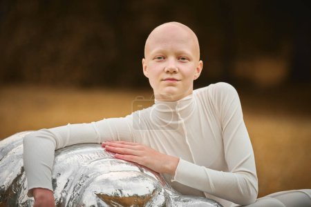 Porträt eines jungen haarlosen Mädchens mit Alopezie in weißem Tuch umarmt Figur der Tardigrade im Herbst Park Hintergrund, glatzköpfige hübsche Teenager-Mädchen Hervorhebung Schönheit in der Umarmung Verletzlichkeit gefunden