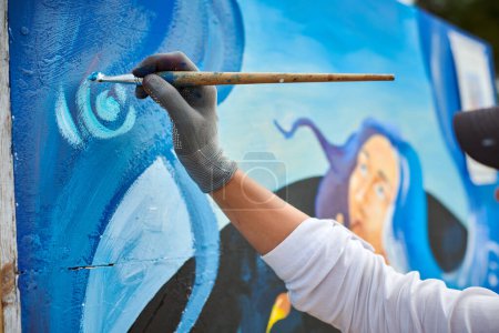 La mano de artista femenina aplica pequeñas pinceladas de pintura con pincel a lienzo creando un cuadro para la exposición, vista de cerca del proceso creativo del pintor de mano femenino