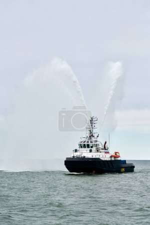 Navire de pompier navigue en pleine mer en dirigeant des jets d'eau vers les côtés démontrant la bravoure salut de l'eau, spectacle nautique de la force maritime russe au défilé des forces navales russes