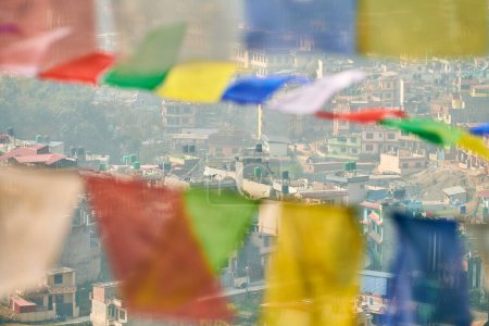 Vista de Katmandú con muchos edificios de poca altura a través de banderas de oración coloridas, vista de la cima de la colina del paisaje urbano de Katmandú creando una mezcla armoniosa de espiritualidad y urbanidad