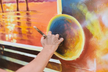 Female painter hand draws picture with paintbrush on canvas for exhibition, close up view of female hand artist painting marvelous picture with small strokes