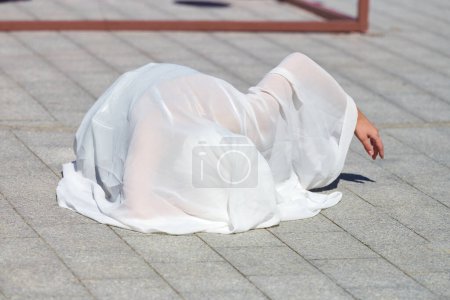 Foto de Artista femenina cubierta de bufanda de seda blanca ondeando con gracia, actuación de danza al aire libre femenina en baldosas de la calle creando sensual y conmovedor espectáculo al aire libre - Imagen libre de derechos