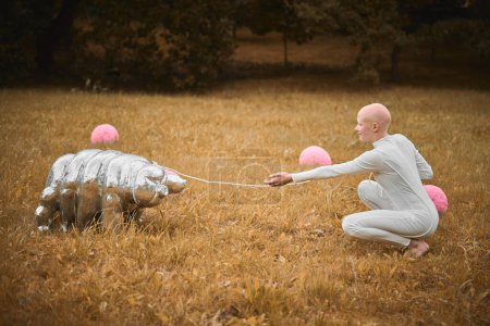 Photo for Portrait of young hairless girl with alopecia in white cloth playing with tardigrade toy in fall park, surreal scene with bald teenage girl reflect on intertwining threads of life and art - Royalty Free Image