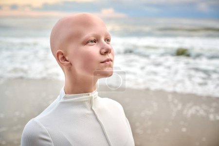 Nahaufnahme Porträt von jungen haarlosen Mädchen mit Alopezie in weißen futuristischen Kostüm auf Meeresgrund, Glatze hübsche Teenager-Mädchen präsentiert einzigartige Schönheit und Identität mit Stolz, ungewöhnliche Alien-Mädchen