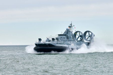 Photo for Hovercraft warship armed with armament sails into sea toward military target to attack and destroy enemy, military hovercraft ship performing strategic maneuver, Russian sea power deployment - Royalty Free Image