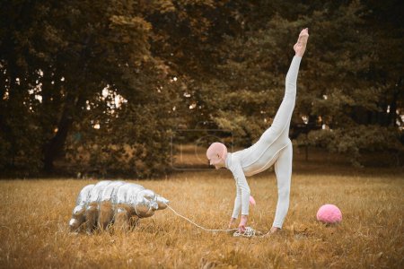 Photo for Portrait of young hairless girl ballerina with alopecia in white cloth playing with tardigrade toy in fall park, surreal scene with bald teenage girl reflect on intertwining threads of life and art - Royalty Free Image