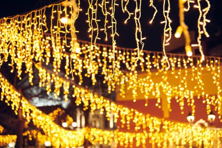 Flackernde Lichter aus hängenden Girlanden für Silvester Straßendekorationen in der Nacht, frohe Weihnachten und fröhliche Neujahrsstimmung mit funkelnden Lichtern Bokeh