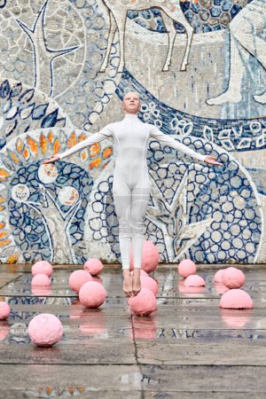 Young hairless girl ballerina with alopecia in white futuristic suit dancing outdoor and jumps among pink spheres on abstract mosaic Soviet background, symbolizes self expression