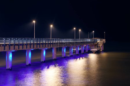 Sea pier adorned multicolored twinkling lights at night symbolizes charm and allure of coastal evenings, beautiful romantic pier decoration beacons of coastal elegance and nighttime beauty