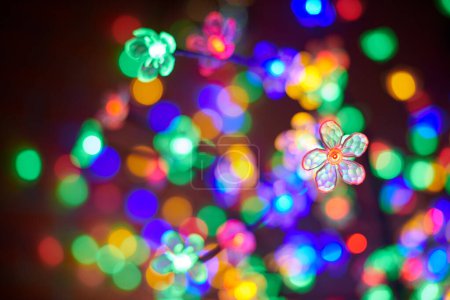 Bunte Girlanden Blume vor dem Hintergrund der bunten Lichter in der Weihnachtsnacht, schöne Silvesterlichter schaffen Atmosphäre des Staunens und Weihnachtszauber
