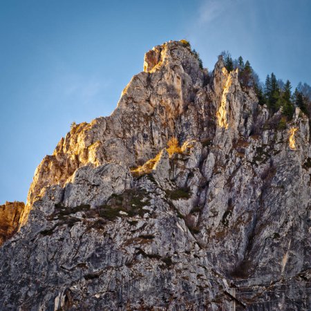 Vista de cerca de un pico rocoso bajo cielos despejados. Las texturas y colores variados revelan detalles intrincados. Sin vegetación. Patrones naturales en superficie de roca rugosa.