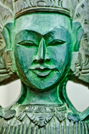 Foto de Escultura de madera verde, intrincadamente tallada, que representa una deidad budista serena. La obra de arte emana tranquilidad y armonía espiritual, mostrando artesanía detallada. - Imagen libre de derechos